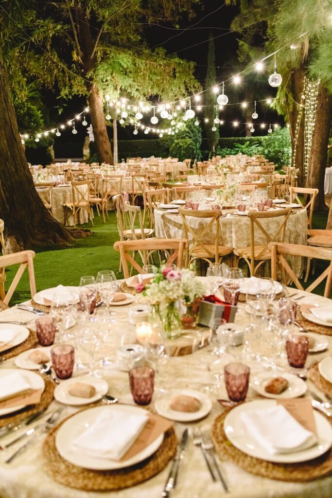 stół w stylu boho wesele z lampkami w ogrodzie wieczorem